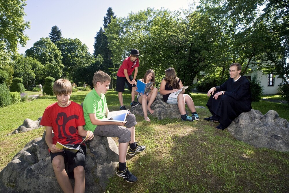 Das Bild zeigt einen Ordensmann mit Schüler:innen