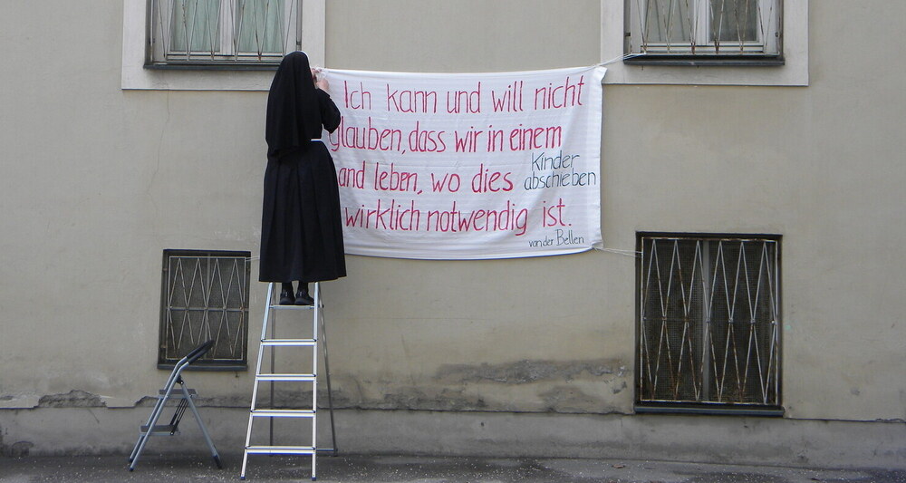 Das Bild zeigt Sr. Notburga, wie sie ein Transparent aufhängt. 