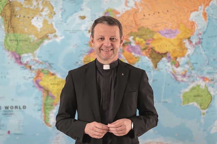 P. Christian Marte SJ im Jesuitenkolleg Innsbruck / SJ-Bild/Christian Ender, Christian Ender P. Christian Marte SJ mit einer Weltkarte im Hintergrund