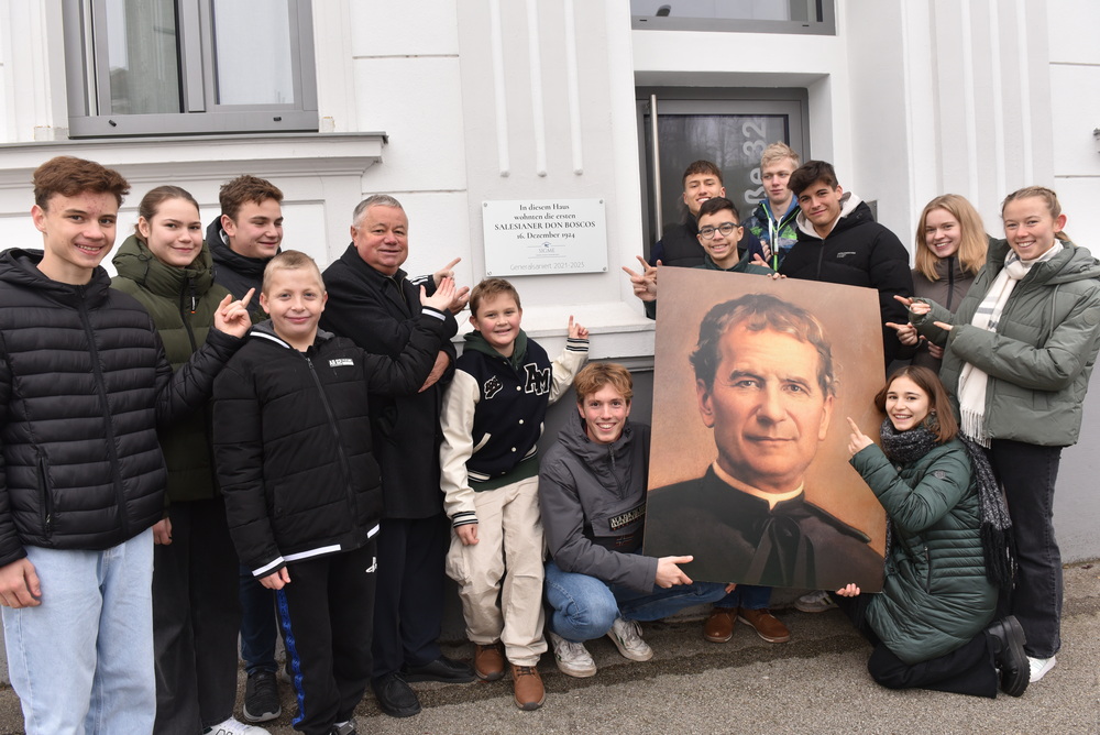 Pater Hermann Sandberger mit Jugendlichen und dem Bild von Don Bosco
