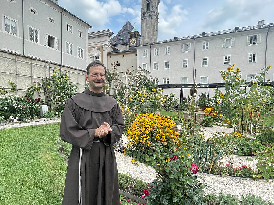 P. Moritz Windegger mit Blick vom Klostergarten auf die Franziskanerkirche.